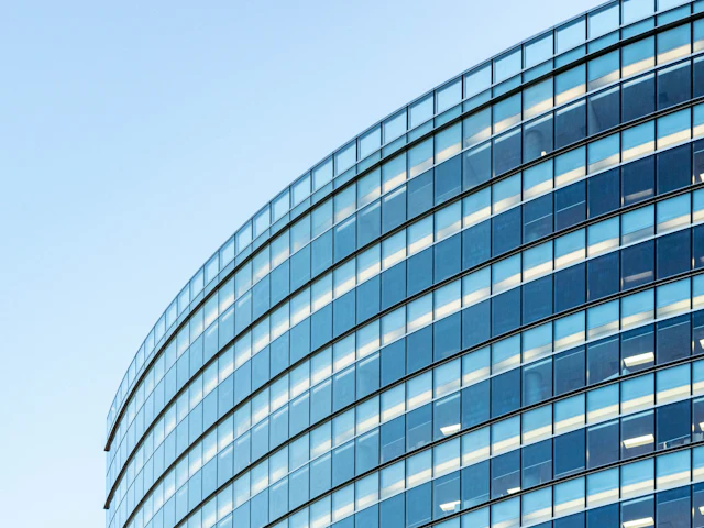 Geschwungene Glasfassade eines Bürogebäudes vor blauem Himmel